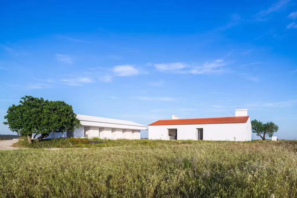 Monte da Azarujinha de Aboim Inglez Arquitectos, edificios blancos con tejado rojo en un prado del Alentejo