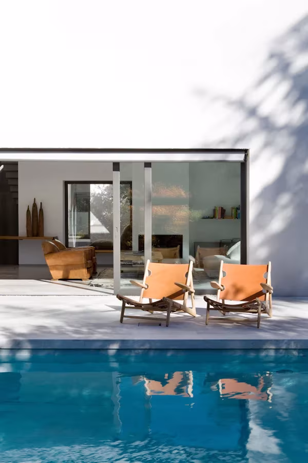 Piscina de la oficina de ÁBATON con dos tumbonas naranjas frente al salón acristalado