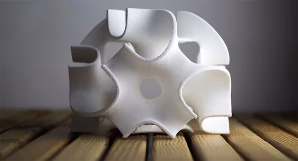 Pieza escultórica de azúcar blanco impresa en 3D con huecos curvos sobre listones de madera