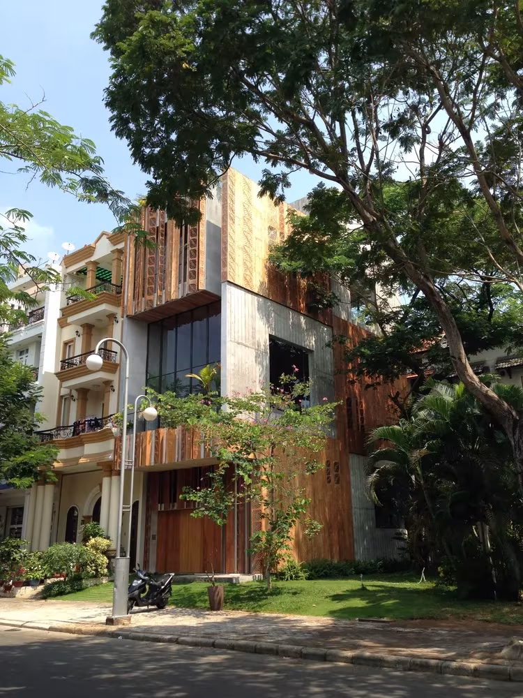 Thong House de Nishizawa Architects en Ho Chi Minh, fachada de madera y hormigón entre árboles