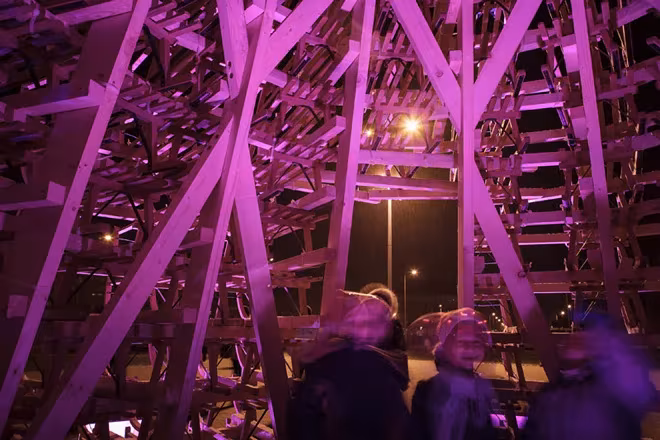 Visitantes dentro del árbol de trineos de Hello Wood, iluminado de noche con luz violeta
