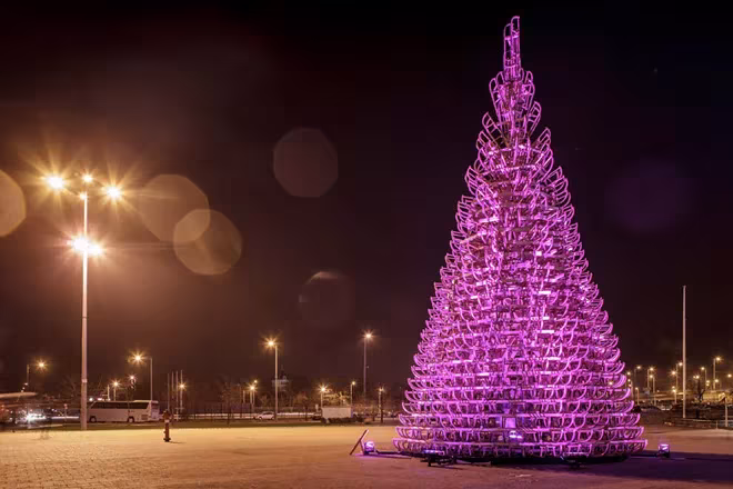 Árbol de 365 trineos de madera iluminado en rosa en una explanada nocturna de Budapest