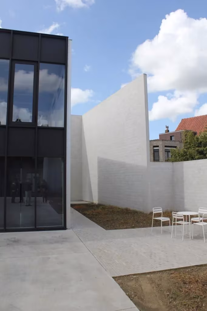 Torre acristalada negra junto a muros blancos y una terraza con sillas en la oficina de Tielt