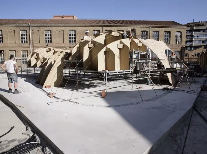 Construcción del pabellón Bricktopia de Map13 con cimbras y andamios en el patio de una antigua fábrica