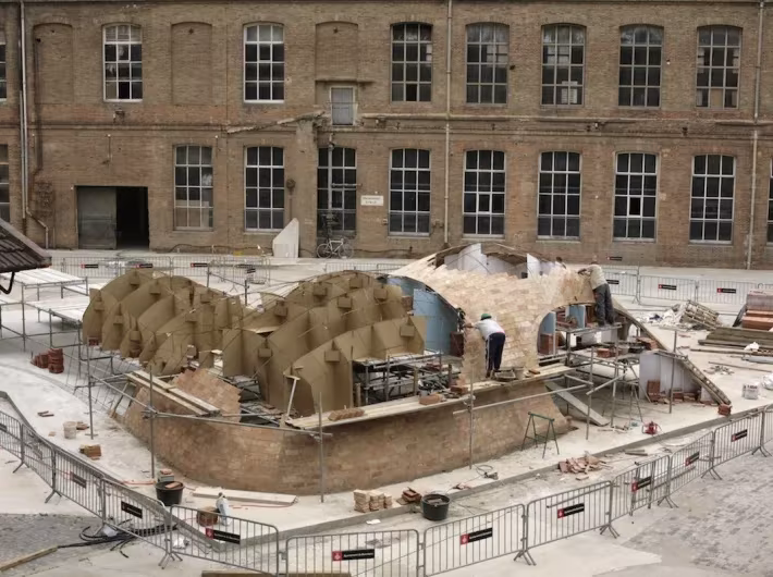 Obra de las bóvedas de ladrillo de Bricktopia vista desde arriba ante una nave de ladrillo de Barcelona
