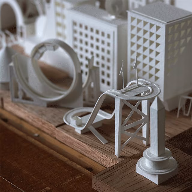 Ciudad en miniatura de papel blanco de Charles Young con edificios, una noria y una montaña rusa