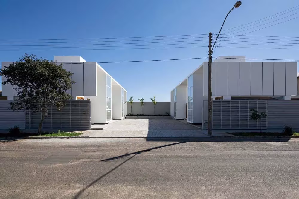 Casas AV de Corsi Hirano Arquitetos en Avaré: dos bloques blancos a ambos lados de un acceso desde la calle