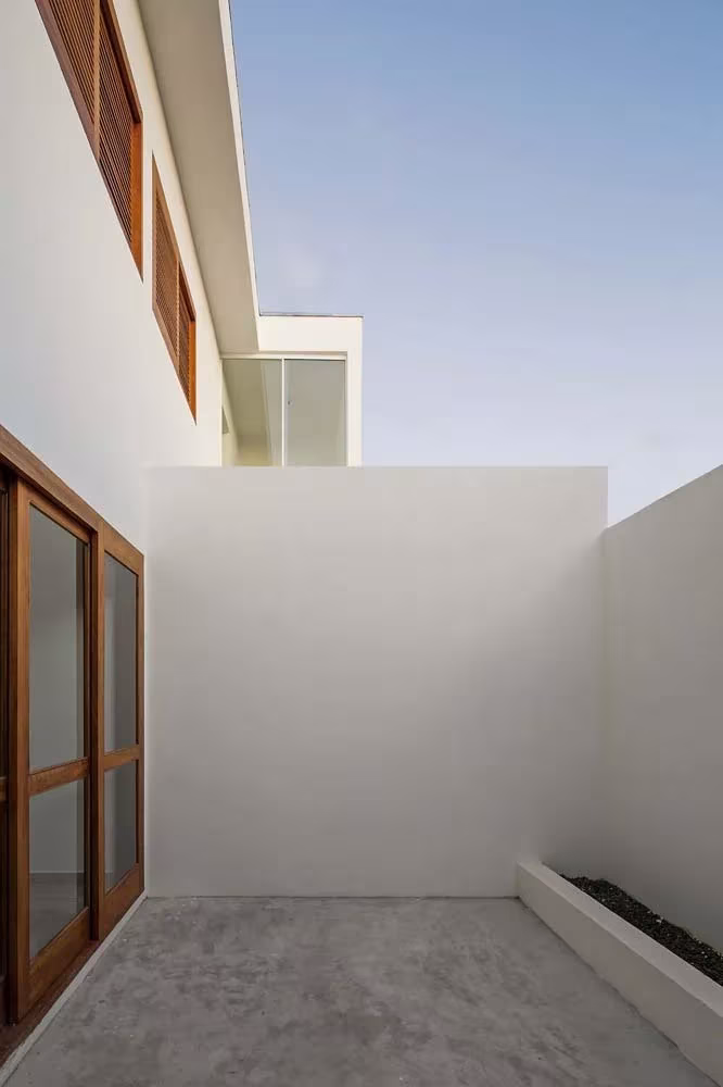 Patio trasero privado de una vivienda de las Casas AV, con muros blancos y carpintería de madera