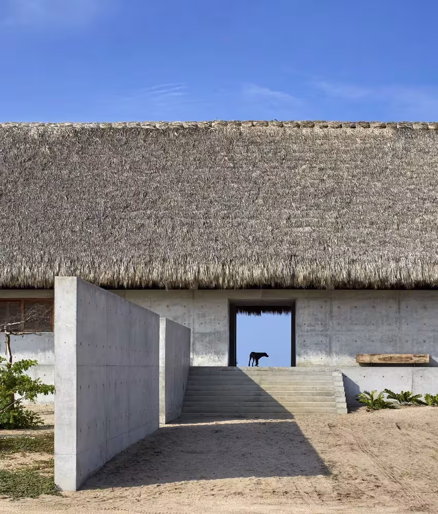 Entrada de la Casa Wabi de Tadao Ando, con cubierta de palma, muro de hormigón y escalera de acceso, en Oaxaca