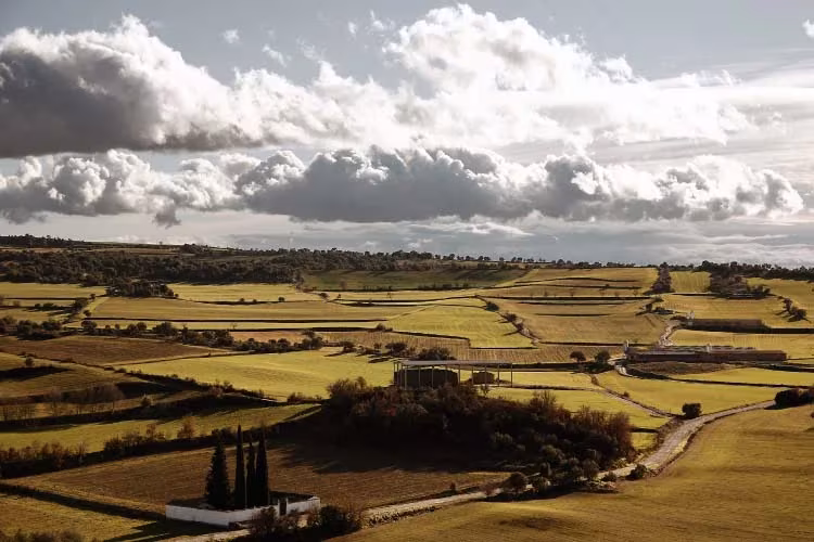 Paisaje de campos de cultivo y colinas de Seró, en Lleida, bajo un cielo con nubes