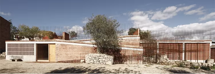 Espacio Transmisor del dolmen de Seró de Toni Gironés: edificio bajo de ladrillo y celosía junto a un olivo