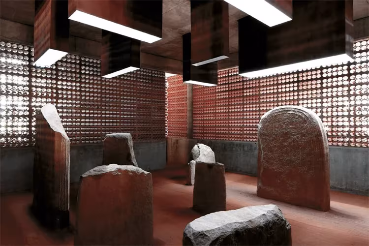 Estelas y piedras megalíticas del dolmen de Seró expuestas bajo lucernarios ante una celosía de ladrillo