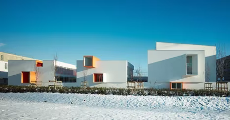 Exterior de las Escuelas Josephine Baker de Dominique Coulon con cubos blancos y ventanas naranjas sobre la nieve
