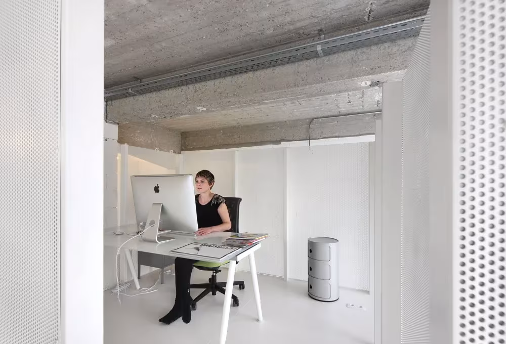 Puesto de trabajo con ordenador en el Loft For, entre paneles de chapa perforada blanca