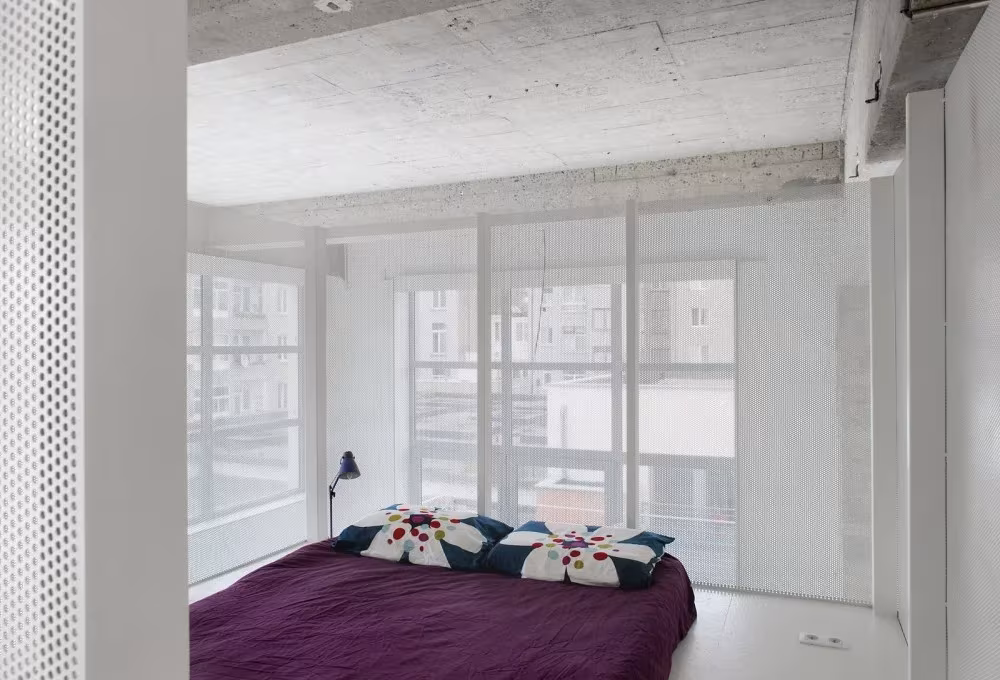 Dormitorio en el altillo del Loft For con cama morada, lámpara negra y ventanales