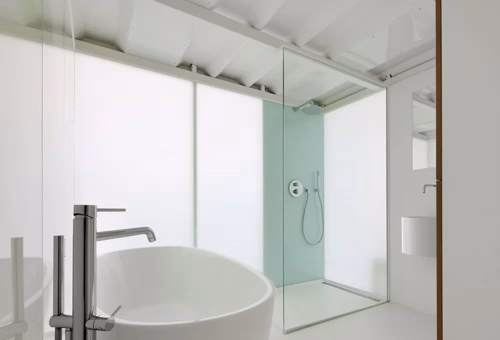 Baño blanco del Loft For con bañera exenta, grifería alta y ducha con mampara de cristal