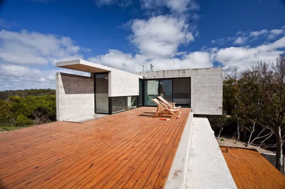 Terraza de tarima de madera en la cubierta de la casa con tumbonas y vistas a la vegetación