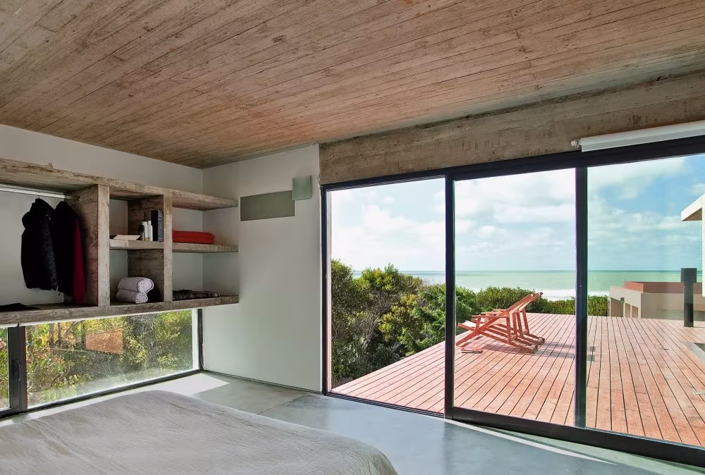Dormitorio con armario abierto de madera y puerta corredera a una terraza con vistas al mar