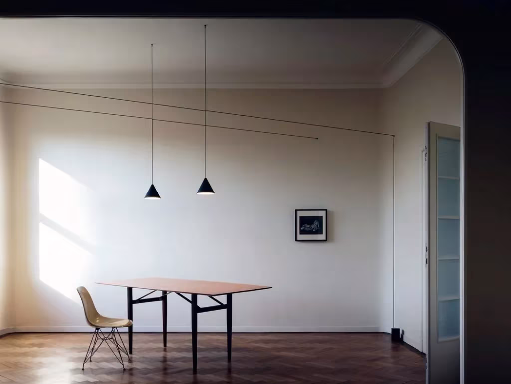 Lámparas String Lights de Michael Anastassiades sobre una mesa en una sala blanca con suelo de madera