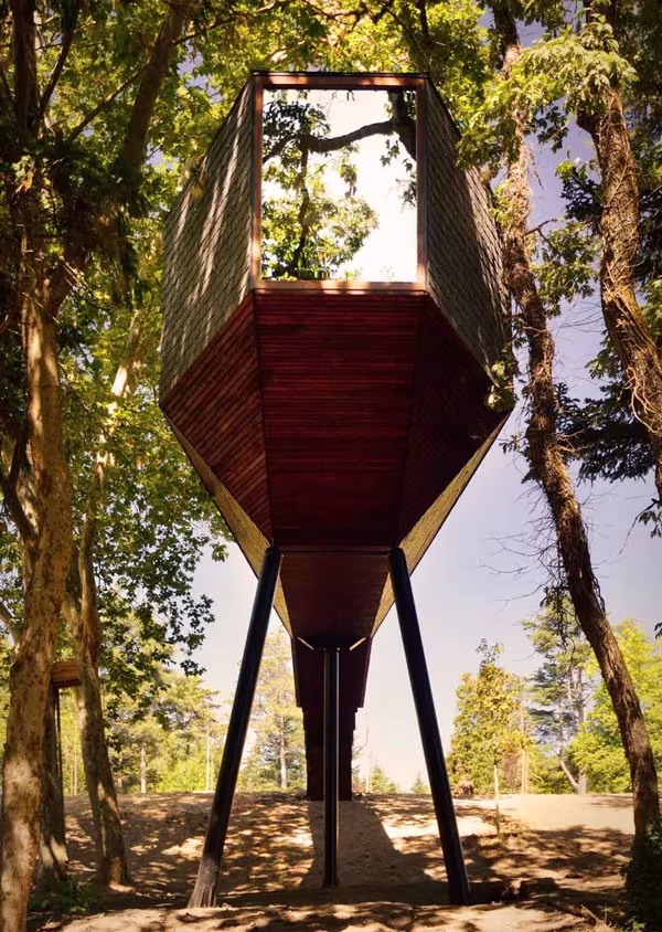 Casa árbol de Rebelo de Andrade en Pedras Salgadas, volumen facetado de madera sobre pilares entre árboles