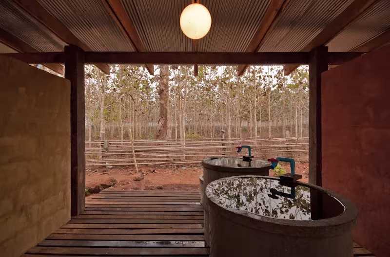 Interior de la casa de baños de TYIN Tegnestue con tinas redondas y suelo de madera abierto al bosque