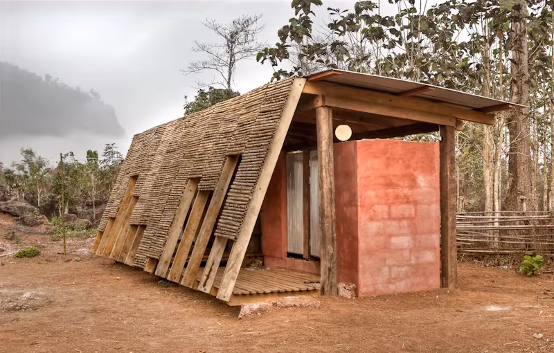 Casa de baños con fachada inclinada de bambú y volumen de ladrillo rojo en el orfanato Safe Haven, Tailandia