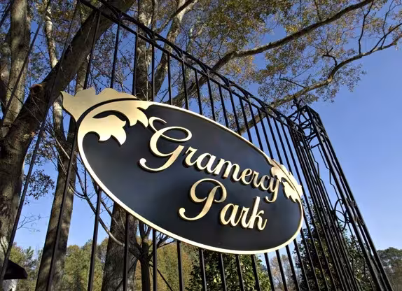 Cartel ovalado dorado y negro de Gramercy Park sobre la verja de hierro forjado