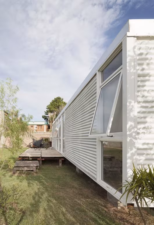 Lateral de la Mia House con ventanas abatibles abiertas y plantas junto a la fachada