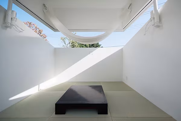 Interior de Paco de Jo Nagasaka con la cubierta elevada, hamaca de tela y tarima negra sobre tatami