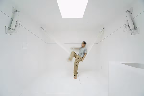 Hombre estirándose en el interior completamente blanco de Paco bajo un lucernario