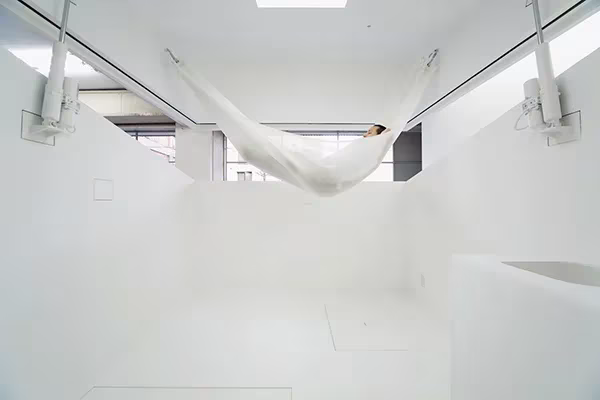 Interior blanco de Paco con la hamaca colgada de herrajes metálicos y la cubierta entreabierta