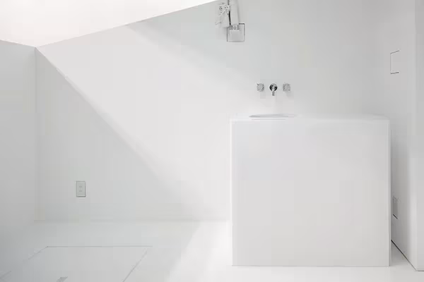 Rincón blanco de Paco con lavabo de bloque macizo y grifo empotrado en la pared