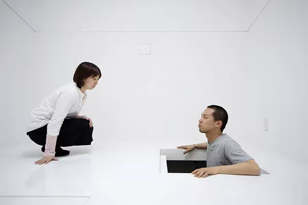 Dos personas conversando en el interior blanco de Paco, una de ellas metida en un hueco del suelo