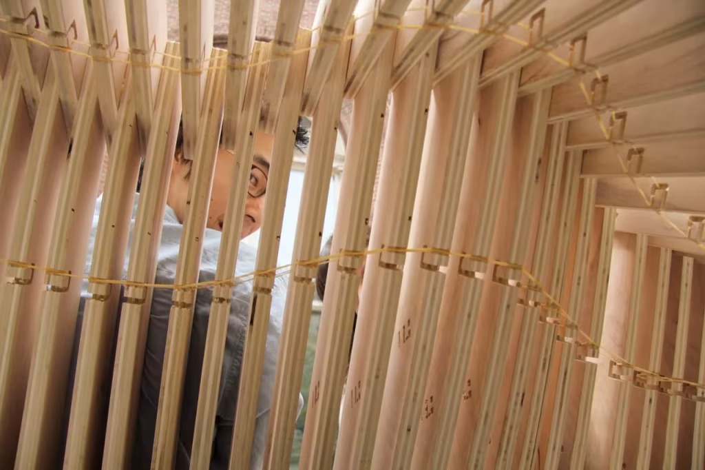 Persona asomándose entre las láminas verticales de madera del banco Polimórfica
