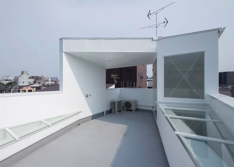 Terraza en la cubierta de la Casa Tamatsu con lucernarios de vidrio y muros blancos