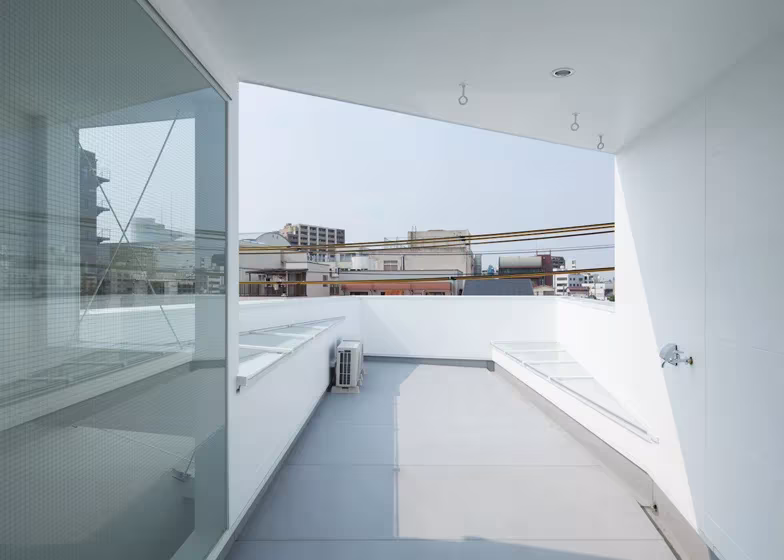 Terraza de la cubierta de la Casa Tamatsu enmarcada por un muro blanco con vistas a la ciudad