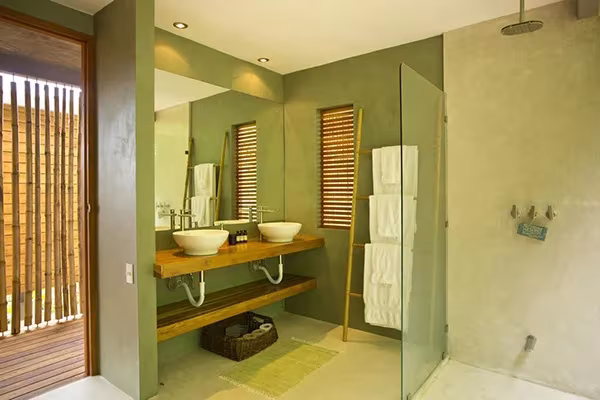 Baño de la Casa Flotante de Benjamín García Saxe con lavabos sobre encimera de madera, paredes verdes y ducha de cristal