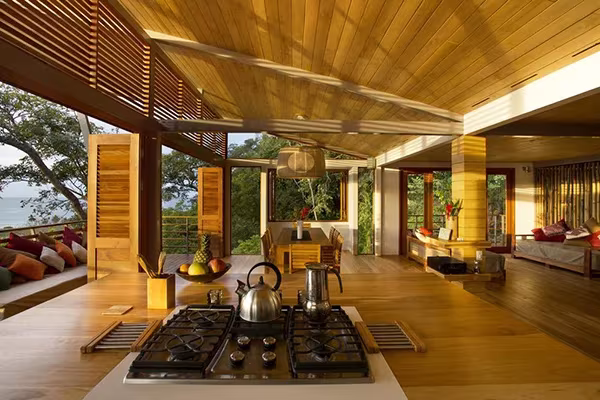 Cocina de la Casa Flotante con placa de gas en isla de madera, abierta al salón y a la selva