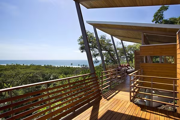 Terraza de madera de la Casa Flotante con cubierta inclinada y vistas a la selva y el océano