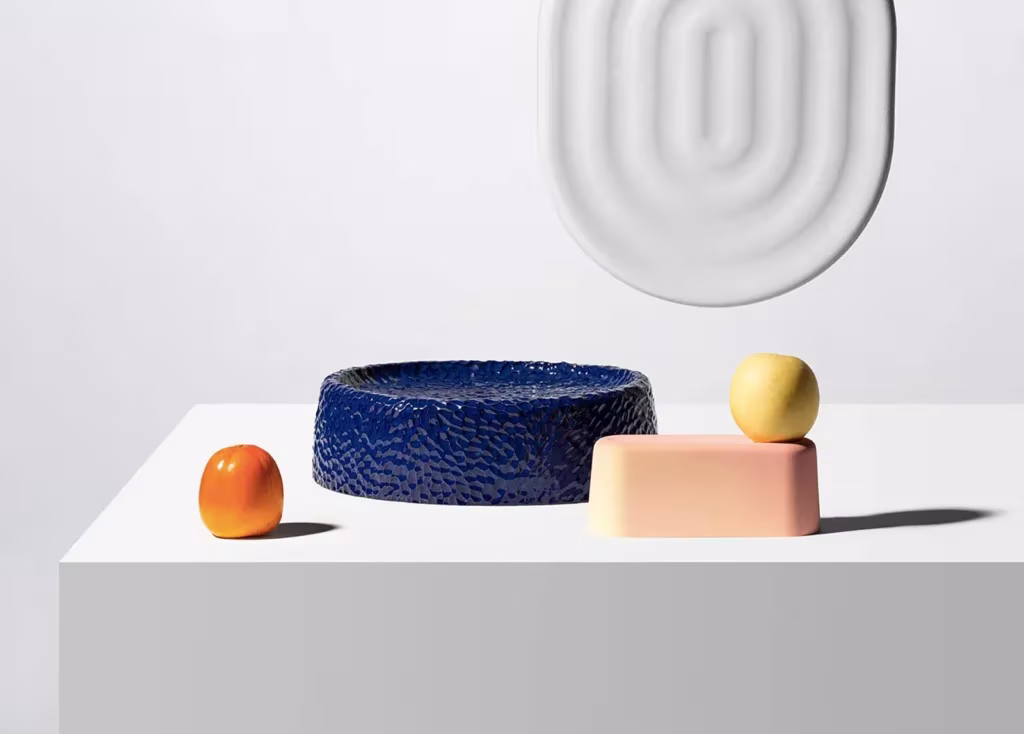 Cuencos y piezas cerámicas de colores de Dimitri Bähler junto a frutas sobre un pedestal blanco