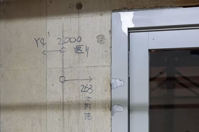 Muro de hormigón de EEl Ekemaguro que conserva las marcas a lápiz de la obra junto a un marco de puerta