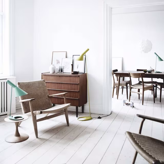 Salón blanco con lámpara AJ de Arne Jacobsen, butacas de Wegner y aparador de madera