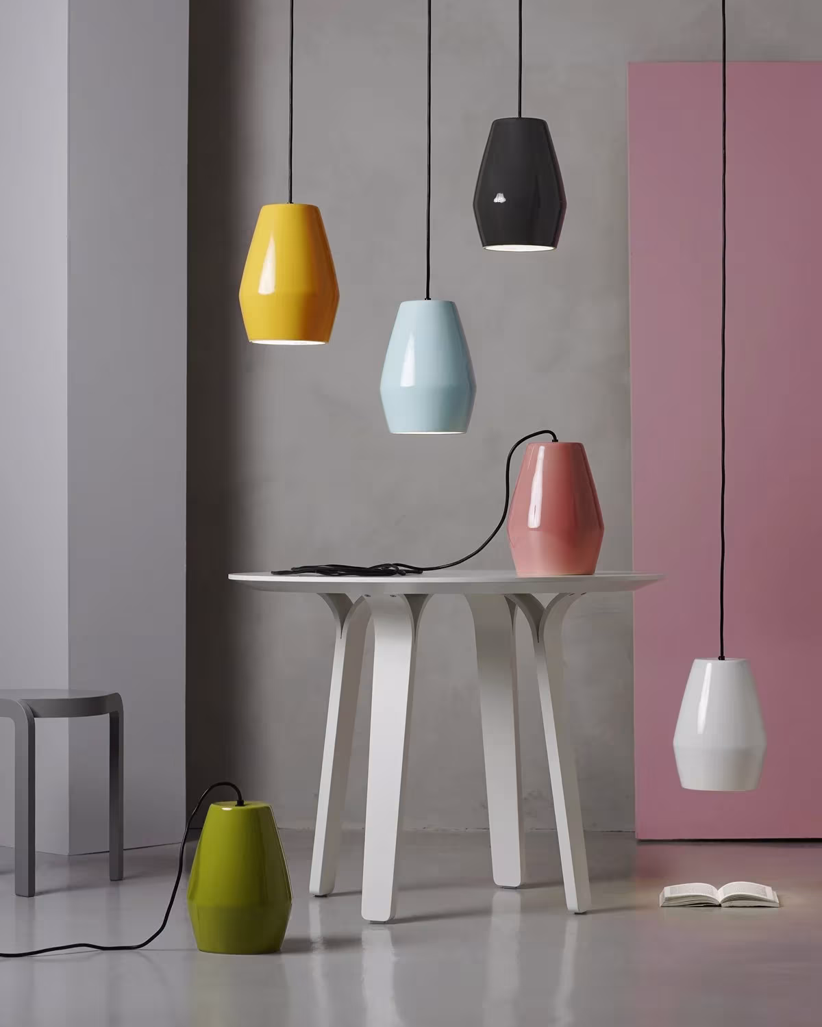 Lámparas colgantes Bell de Northern Lighting en amarillo, azul, rosa, negro y blanco sobre una mesa blanca