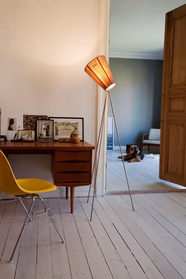 Lámpara de pie Oslo Wood de Northern Lighting con pantalla de madera junto a un escritorio y silla amarilla