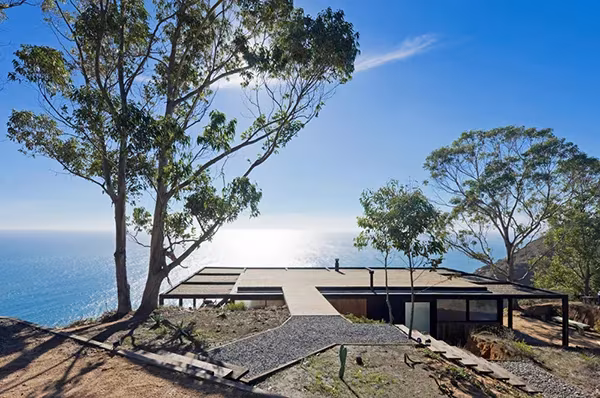 Casa Till de WMR Arquitectos, cubierta plana entre árboles en un acantilado sobre el mar