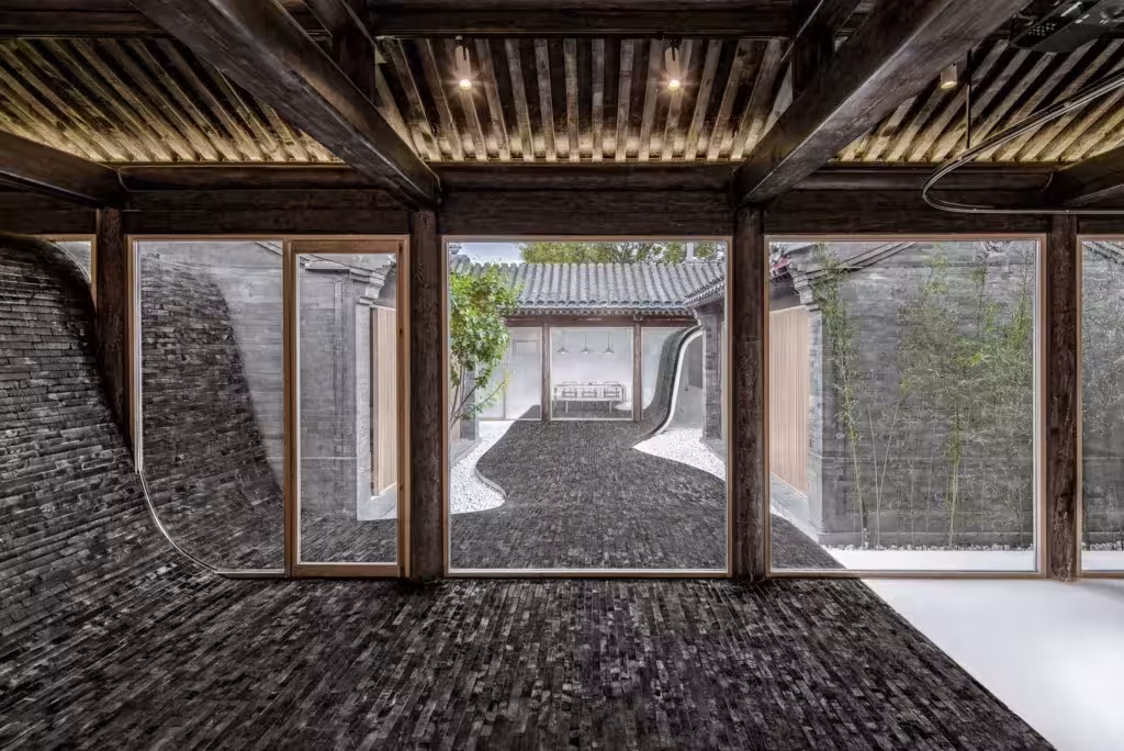Suelo de ladrillo gris ondulado que trepa por las paredes en la Twisting Courtyard House de Arch Studio, Pekín