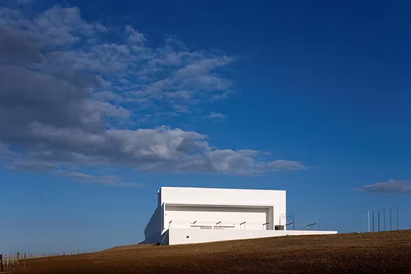 Bodega Adega Maior de Álvaro Siza, volumen blanco sobre una loma bajo un cielo azul intenso