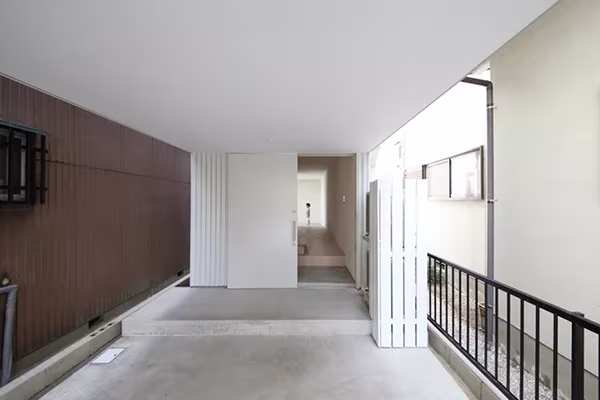 Pasillo alargado de hormigón con barandilla negra y paredes blancas en la Imai House de Katsutoshi Sasaki