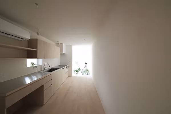 Cocina lineal de acero y madera clara a lo largo de la estrecha Imai House, en Aichi