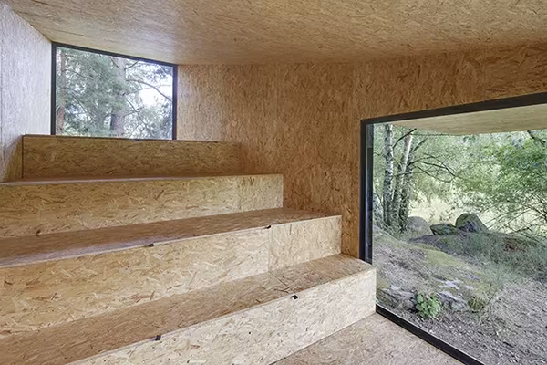 Interior de la Cabaña en Bohemia de Uhlik Architekti con gradas de tablero OSB y ventanal al bosque